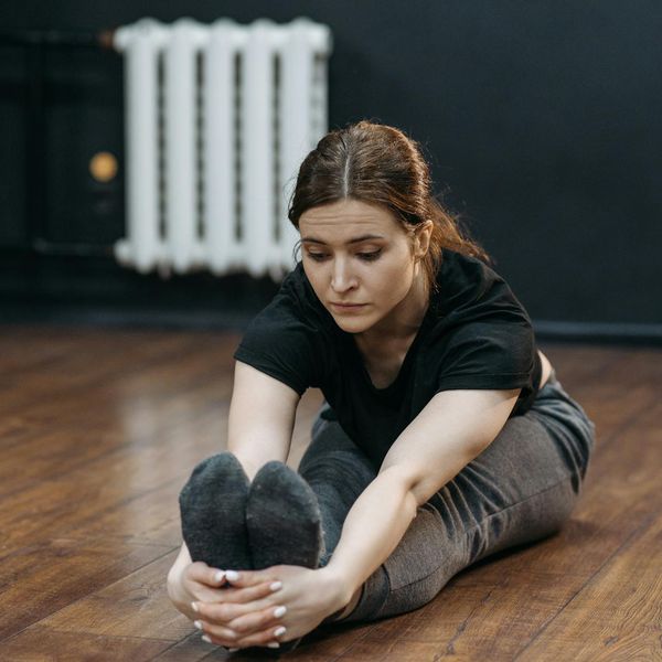 Woman in a calm seated yoga pose surrounded by a lavender glow.